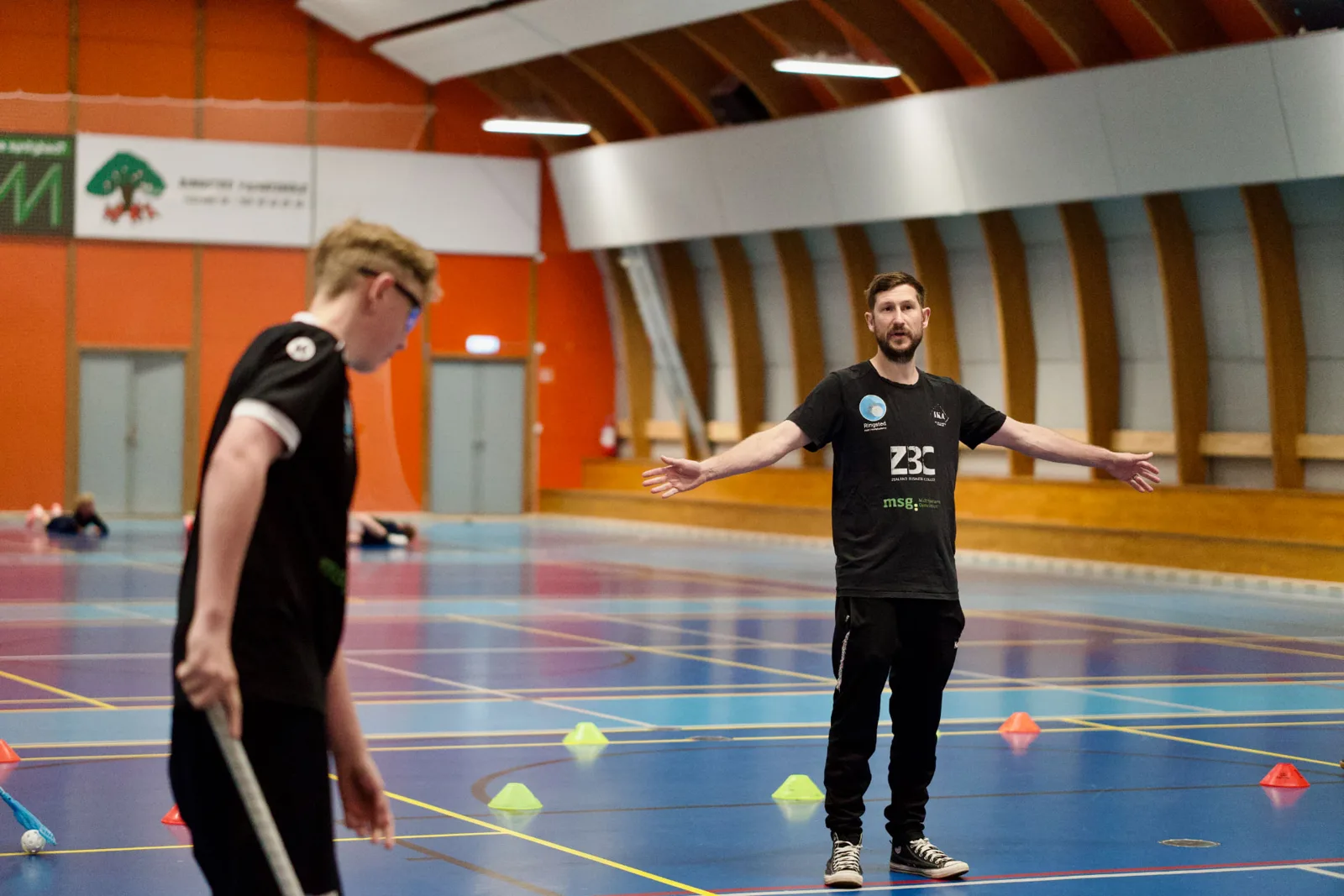 Træner instruerer floorballspiller i hallen
